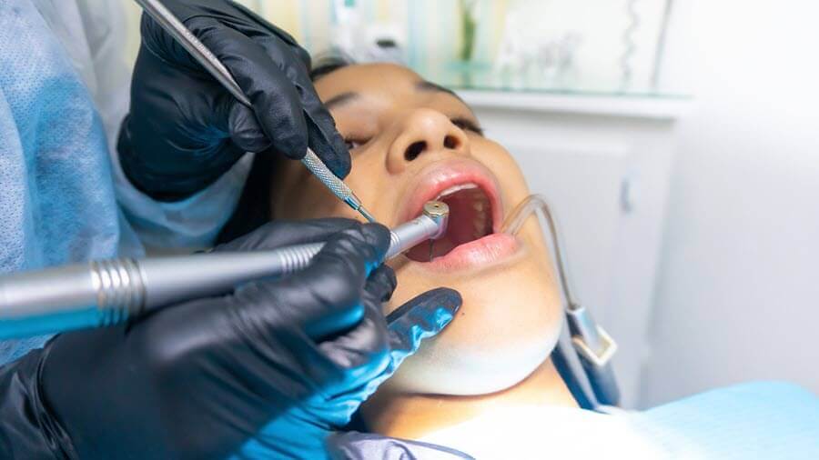 Dentist with drill in patient's mouth.
