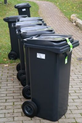 Picture of several grey industrial bins lined up along a sidewalk.