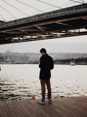 Man standing on wharf looking at mobile phone.