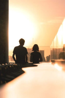 Two people standing on balconey admiring the sunset.