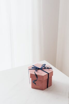 Gift box with blue ribbon sitting on table representing TheGoodyBox.com domain name.