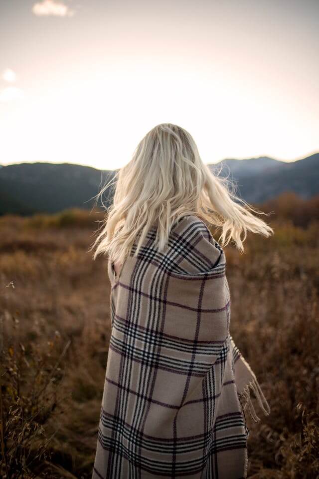 Woman sitting on rock looking at field.