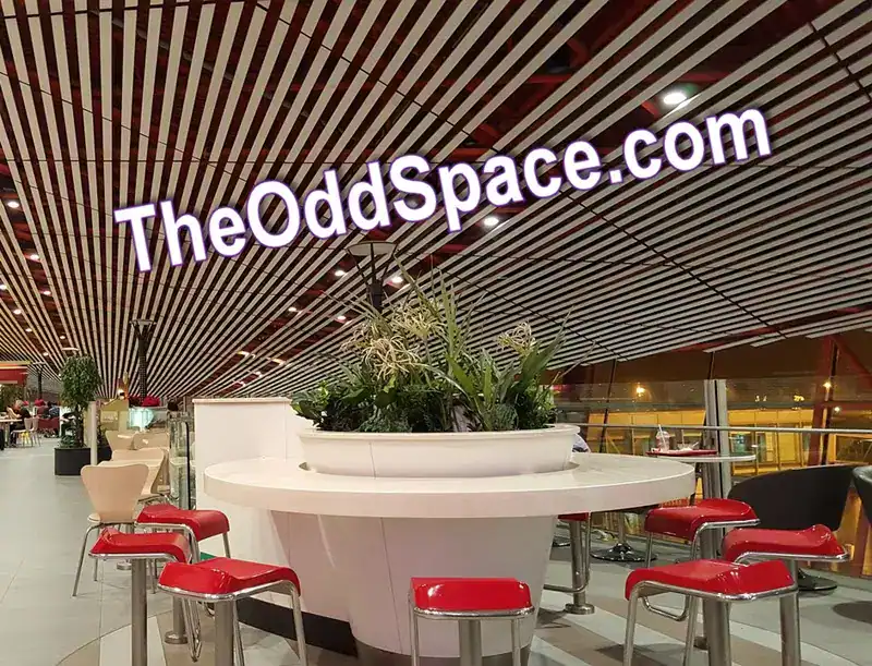 TheOddSpace.com logowith bold text and a colorful meeting area background with round table and chairs.